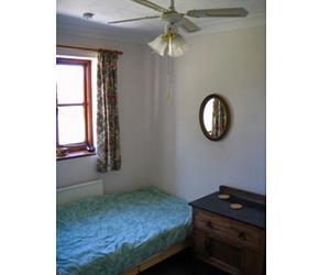 Pretty green single bedroom with ceiling fan for summer cooling. Also bedside table, closet and dressing table.