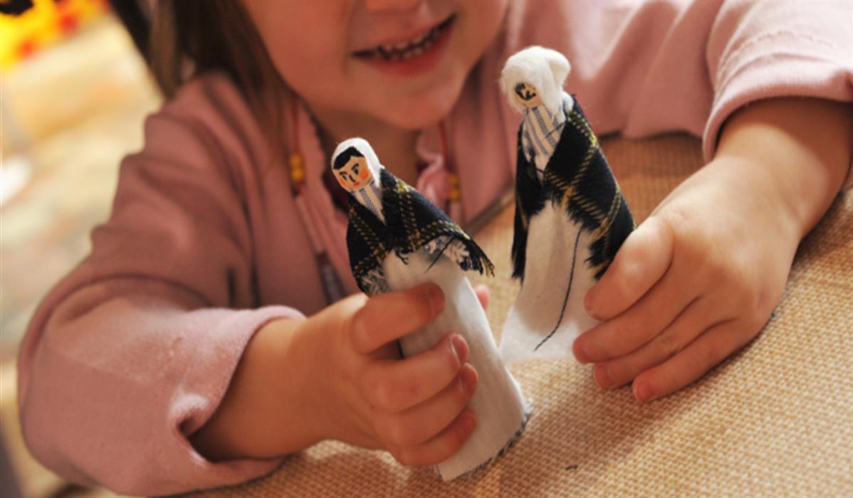 Showing a child playing with hand-made figures.