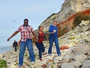 A family of three walking alongside the famous red and white striped cliffs of Old Hunstanton, west Norfolk.