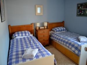 The second bedroom of the property with twin beds and a  shared beside table. Each bed has a white towel on it.