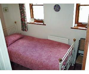 Pink themed single Bedroom with ceiling fan to keep cool in the summer. Also bedside table, and wardrobe.
