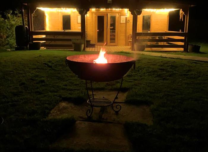 Showing the garden area and lit fire pit at night.