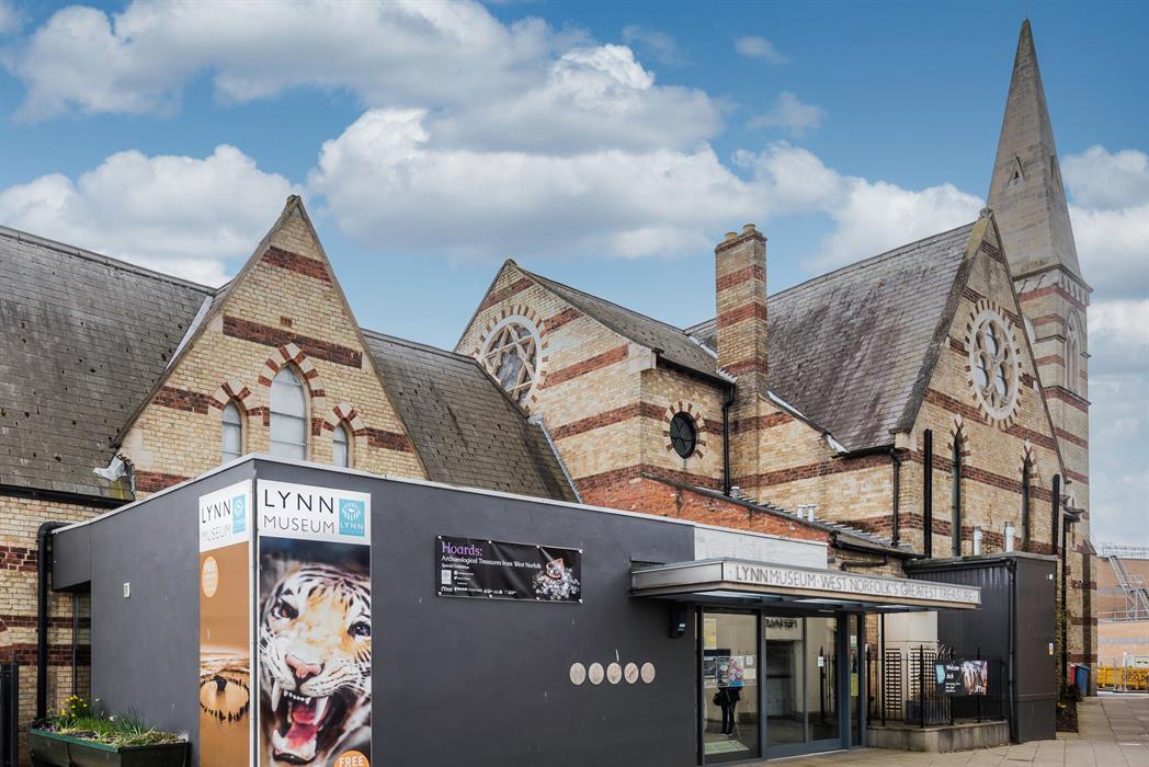 A view of Lynn Museum's front entrance from the left. The museum's chapel spire can be seen rising up in the background.