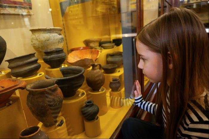 Image of a child looking into a glass display case of Viking pottery