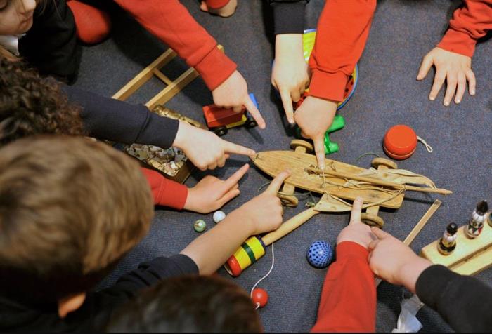 Image of children's hands playing with a wooden toy.