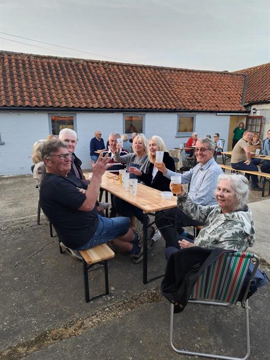 People outside raising their glasses of cider.